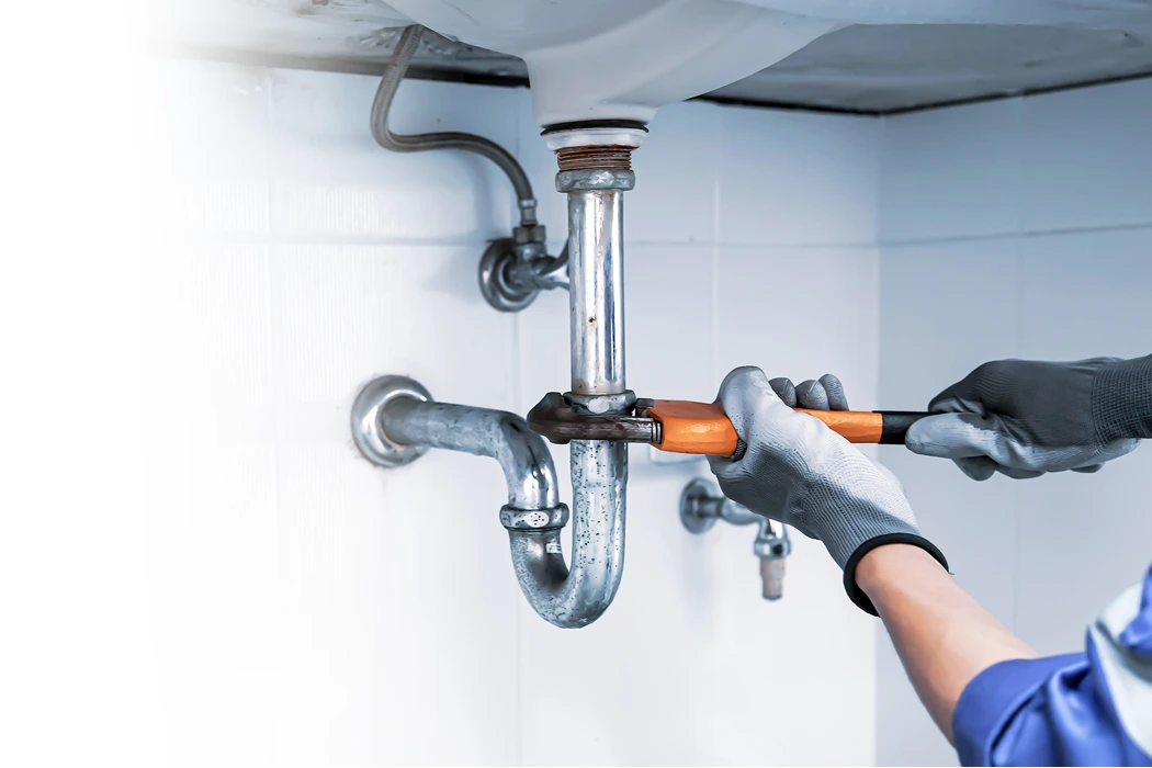 tech repairing pipe under a sink